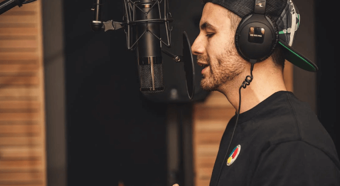 A male voice artist recording in a studio.