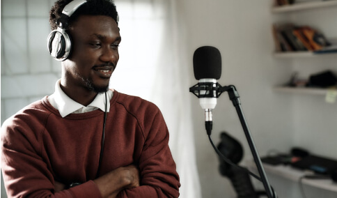 A voice over artist standing in front of a mike to provide a voice over
