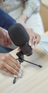 A woman setting up a microphone on a flat surface for a podcast